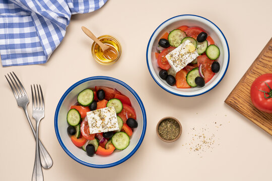Greek salad with tomatoes cucumber bell pepper olives feta cheese and olive oil in bowl on light beige background, Mediterranean healthy food concept