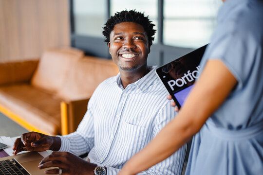 Man Smiles While Reviewing Portfolio at Cafe in the Afternoon