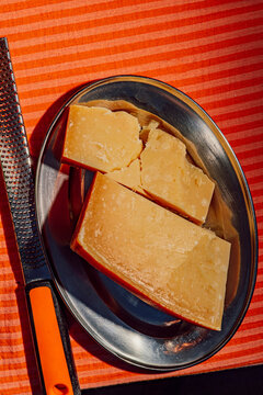 Aged parmesan cheese block on a plate next to a microplane grater