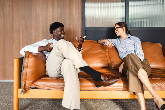 Colleagues Share a Conversation on a Couch in a Casual Setting