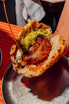 Chef pouring spicy chili oil onto a gourmet meat kofte pita