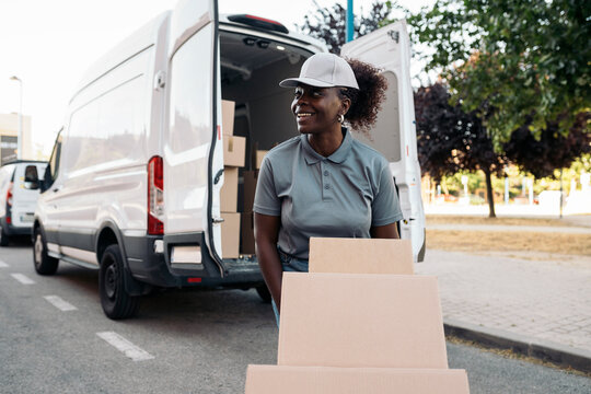 Happy black woman courier delivering packages from van