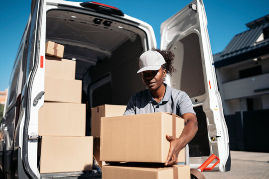 Black woman courier delivering packages from van