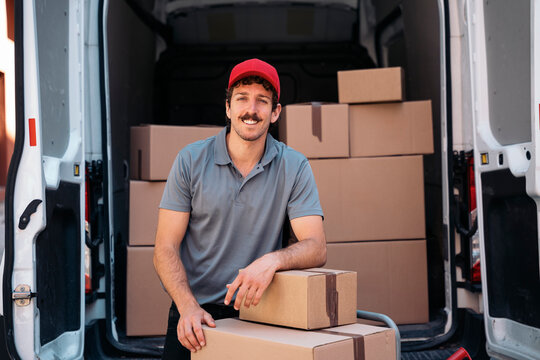 Smiling delivery man wearing hat with packages