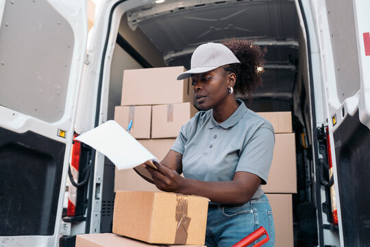 Woman courier checking packages in delivery van