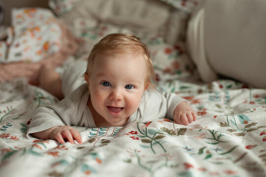 A baby grins during tummy time on a floral blanket