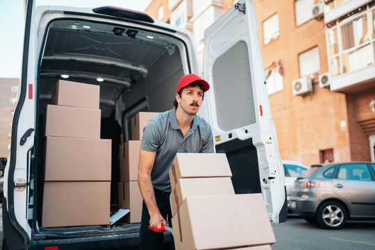 Delivery man unloading boxes from van for shipping