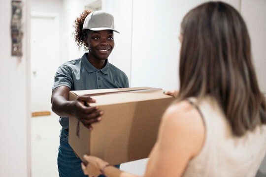 Delivery woman handing carton package to customer