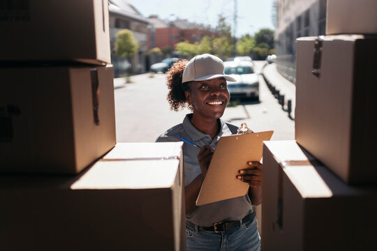 Delivery woman organizing packages, checking shipping list