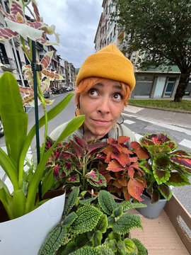 Woman holding plants on a street in an urban area during the day