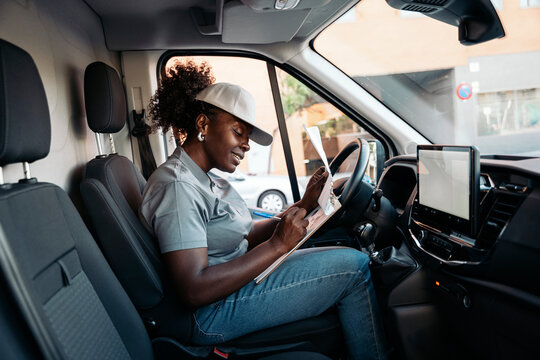 Female delivery driver checking papers in delivery van