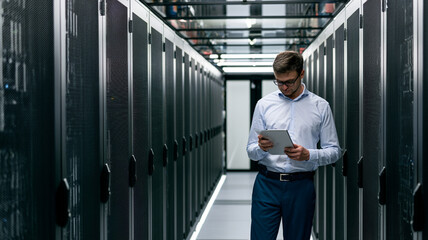 Fototapeta premium Data Center Technician Monitoring Server Infrastructure With Tablet