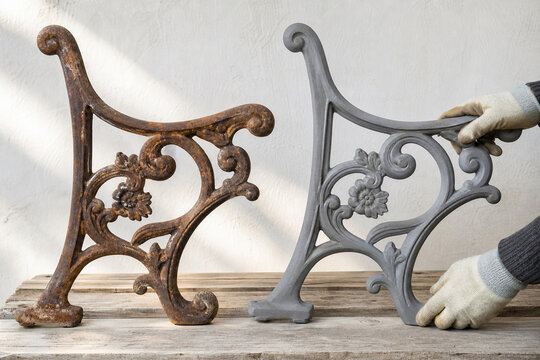 Worker comparing rusted and sandblasted metal bench leg. Restoration of old furniture by industrial cleaning. Metal surface finishing and debris removal process for home renovation.