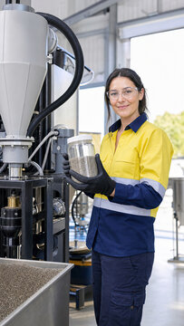 Woman technician holding jar of abrasive media for sandblasting machine. Professional worker in factory inspecting material for metal cleaning. Industrial process and manufacturing concept.