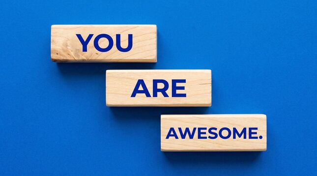 Inspirational message you are awesome on wooden blocks against blue backdrop for personal motivation and positive affirmation.