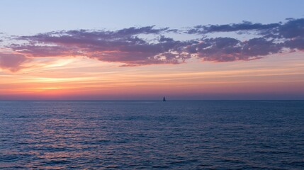 Fototapeta premium The Sailboat on a Tranquil Sunset Ocean Horizon with Soft Clouds
