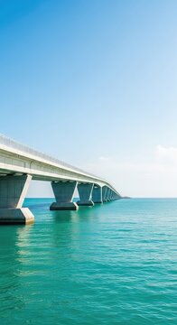 An expansive modern concrete bridge stretches across calm turquoise ocean waters toward the horizon under a clear blue sky at high noon, endless, outdoors, modern