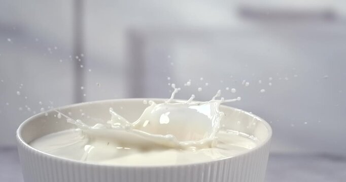 Strawberry falling into a bowl of milk with splash in super slow motion