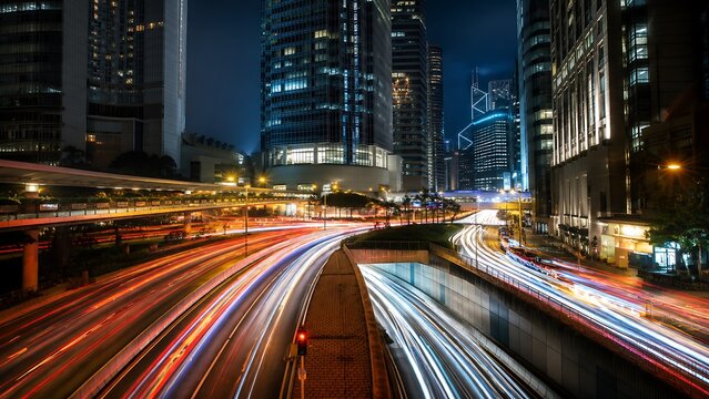 Long exposure night cityscape of modern skyline with light trails from heavy traffic flowing on highway bridges.