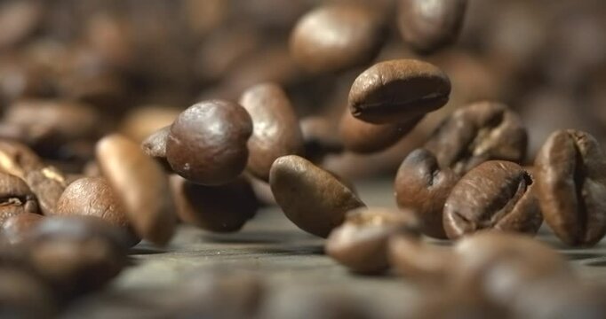 Roasted coffee beans bouncing across wooden table in super slow motion