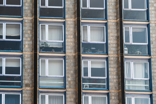Symmetrical rows of windows on a brick apartment building facade with colorful window frames