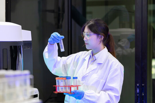 Laboratory technician conducts experiments with test tubes and microscope in a modern research facility