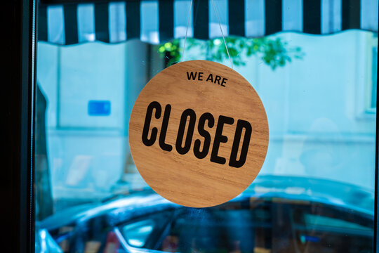 Round wooden closed sign hanging on shop window