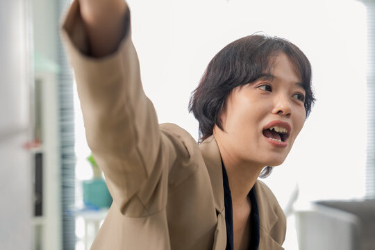 Confident businesswoman pointing at whiteboard chart, explaining strategy and presenting data during office meeting, close-up dynamic angle capturing leadership and business presentation concept