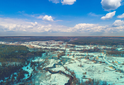 Aerial view of rural landscape at sunset. Top view of a narrow winding river and countryside in a snowy winter;