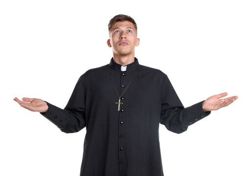Young priest in cassock praying on white background