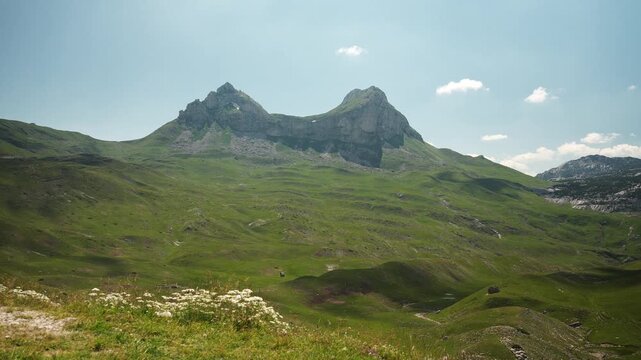 Rocky mountain peaks rise above rolling alpine meadows at Sedlo Pass in Durmitor National Park. The dramatic landscape showcases the wild beauty of Montenegro during summer