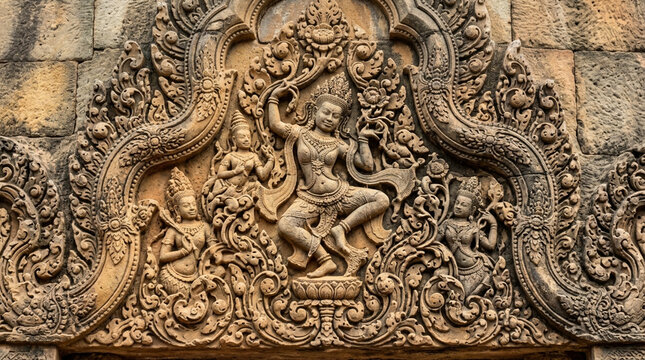 Ancient Khmer bas-relief carving of dancing Apsara figures in intricate detail.