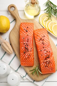 Pieces of raw salmon with spices on white wooden table, flat lay