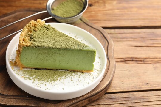 Piece of tasty matcha cheesecake, powder and sieve on wooden table, closeup. Space for text
