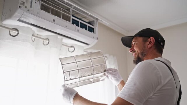 Shocked HVAC technician holding and inspecting a heavily soiled air conditioner filter. Professional maintenance, AC cleaning, dirty filter and unexpected repair problem concept.