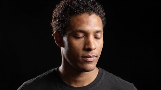 Young Mixed-Race Man Opening Eyes in Dark Studio
