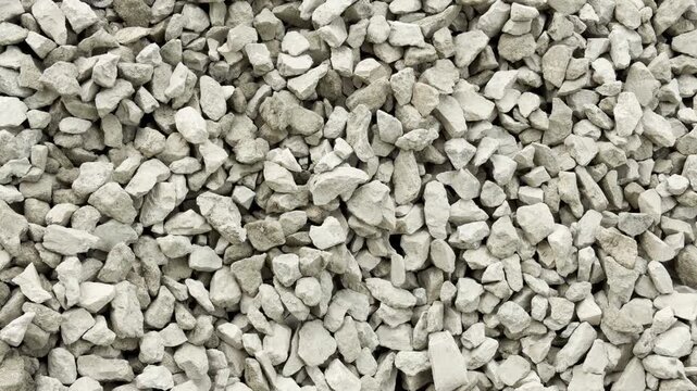 Grey crushed stones spread across the industrial ground. The rough pebbles fill the tight space. This raw texture evokes a cold, sterile feeling of harsh reality.