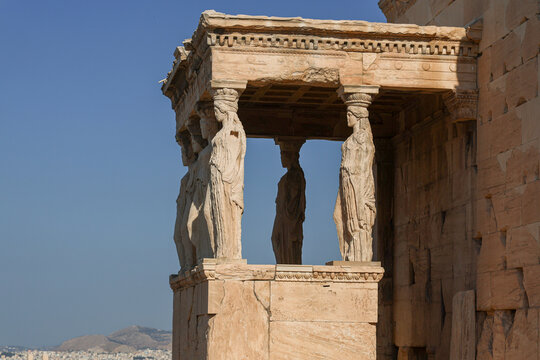 Side view of the Erechtheion&rsquo;s Porch of the Caryatids on the Acropolis of Athens, showing sculpted female columns supporting the ancient marble entablature under bright sunlight.