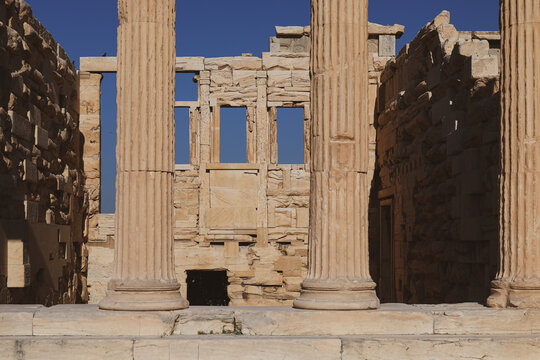 Detailed view of the Erechtheion&rsquo;s marble columns and inner stone walls on the Acropolis of Athens, revealing ancient craftsmanship and classical architectural precision under clear sunlight.