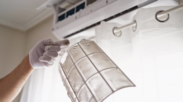 Technician in gloves showing a dirty and dusty air conditioner filter needing cleaning and maintenance, highlighting the need for regular hvac system service for home health
