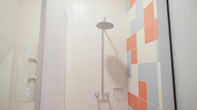 Clean bathroom interior displays shiny pedestal sink mirror and shower stall. Light tiled surfaces create fresh hygienic environment