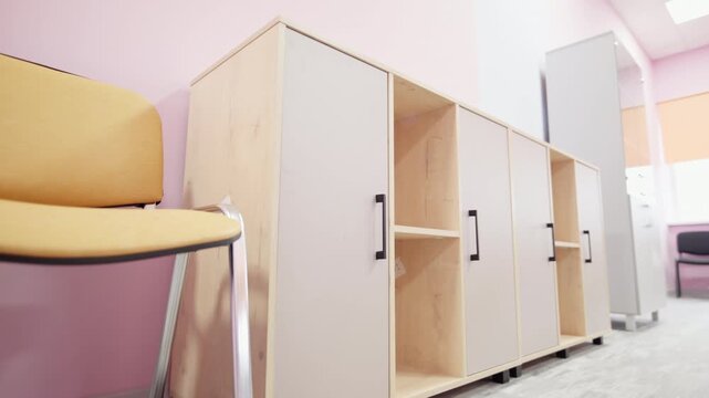 Cabinet features beige doors and black handles near office chairs. Functional setup offers practical space management in clinic hall