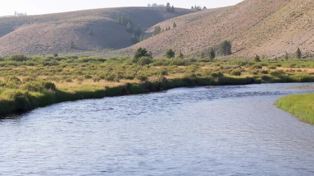 Clear river flows gently through a grassy valley