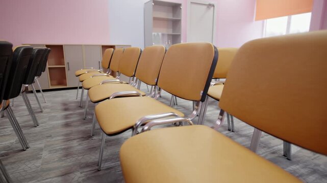 Rows of colorful chairs fill bright conference room floor. Functional furniture setup offers comfortable seating arrangement for events