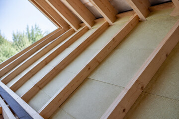 Trabajo de construcción en una estructura con vigas de madera y material aislante en un edificio nuevo © milanchikov