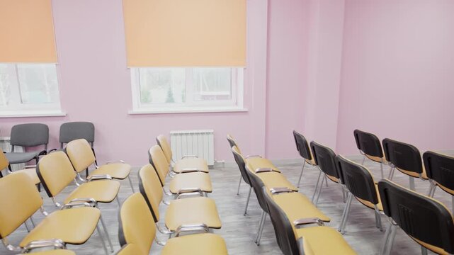 Dark chair backrests line up across light wood-patterned floor. Classroom interior creates professional and quiet learning atmosphere