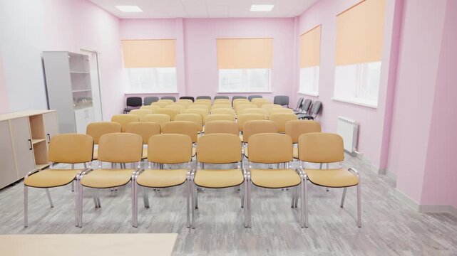 Empty conference room features multiple rows of seating for events. Organized interior creates professional yet comfortable environment