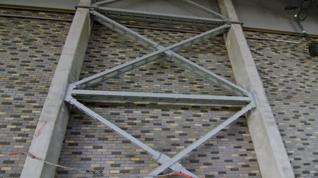 Steel X-bracing truss frame reinforces brick accent wall in industrial building. Strong elements provide essential seismic and load support