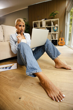 Woman Working in a Small Office at Home While Sitting on the Floor With Laptop