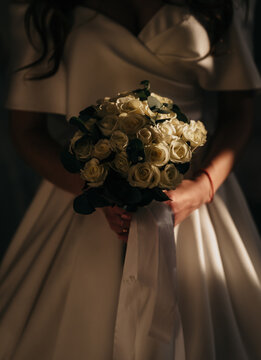 Bride in White Wedding Dress Holding Cream Rose Bouquet